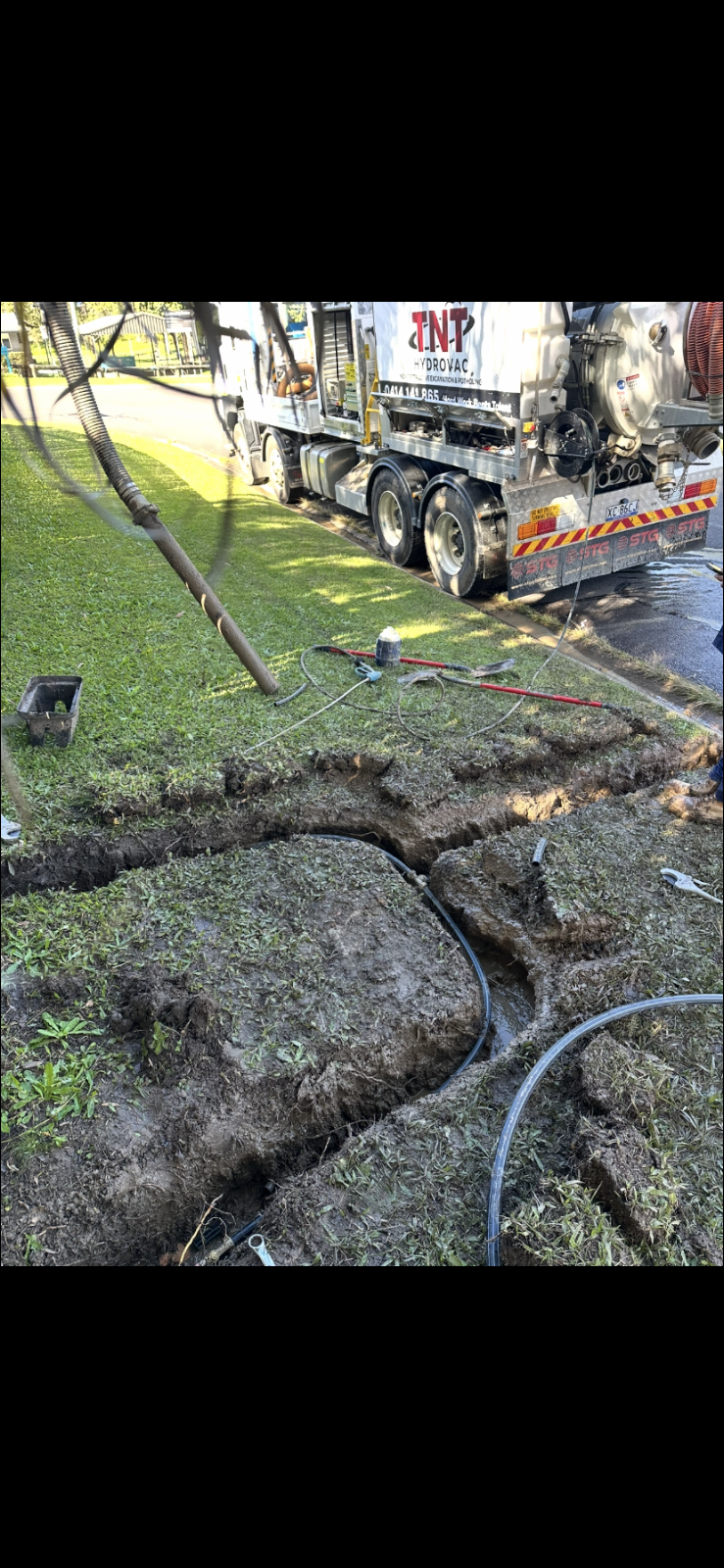 TNT HydroVac truck and open trench beside a grassed area TNT HydroVac truck and open trench beside a grassed area