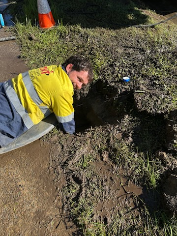 Worker in high-visibility clothing beside a roadside excavation Worker in high-visibility clothing beside a roadside excavation