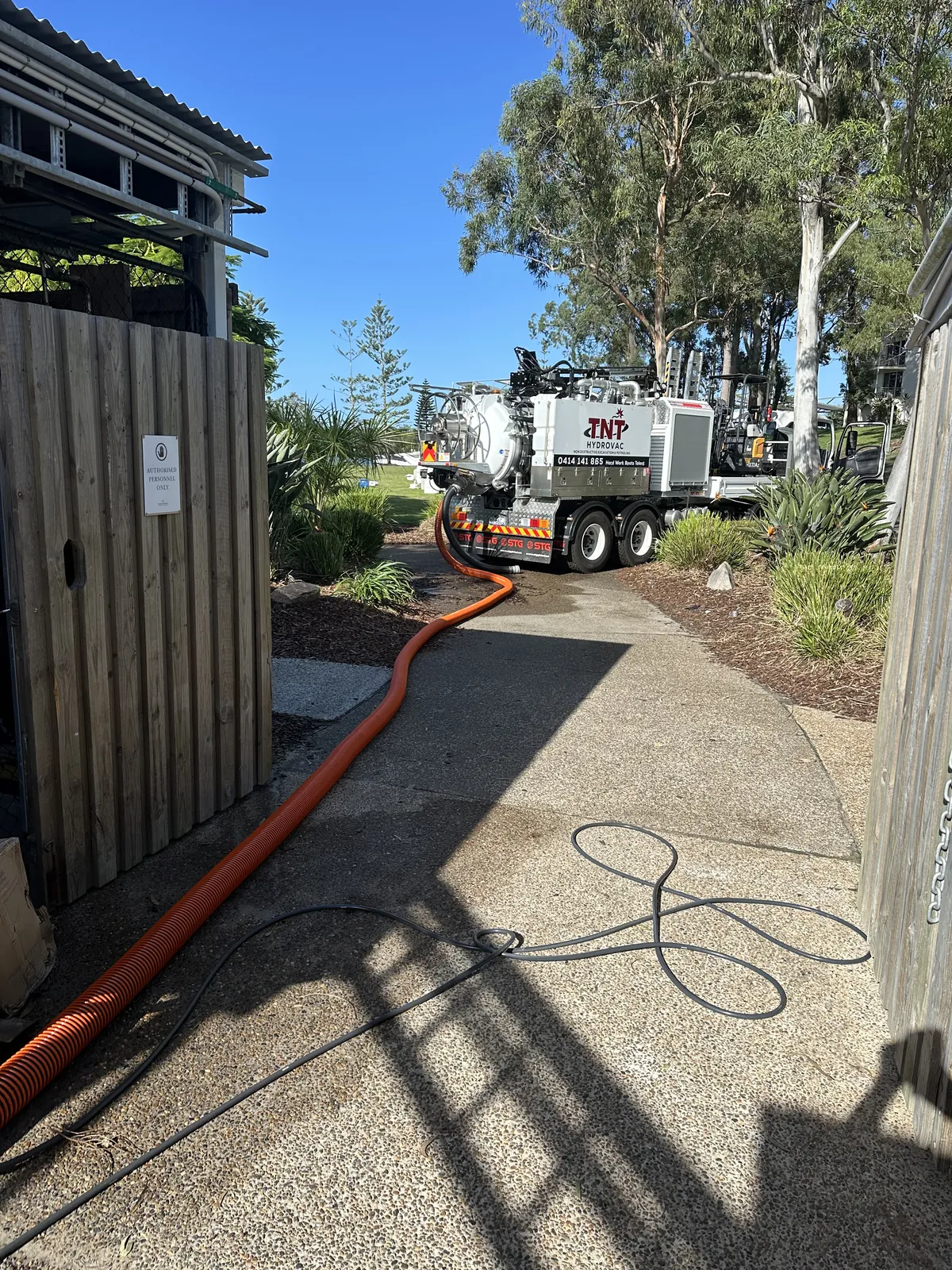 Long hose run in Pacific Pines Orange vacuum hose following a narrow path beside a fence towards the truck
