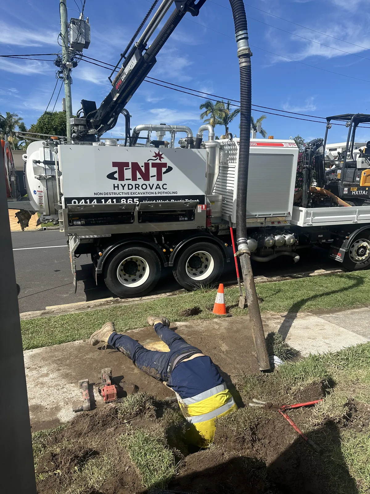 NDD potholing in Bundall Worker in an excavation beside the truck with a vertical vacuum hose and service fittings visible