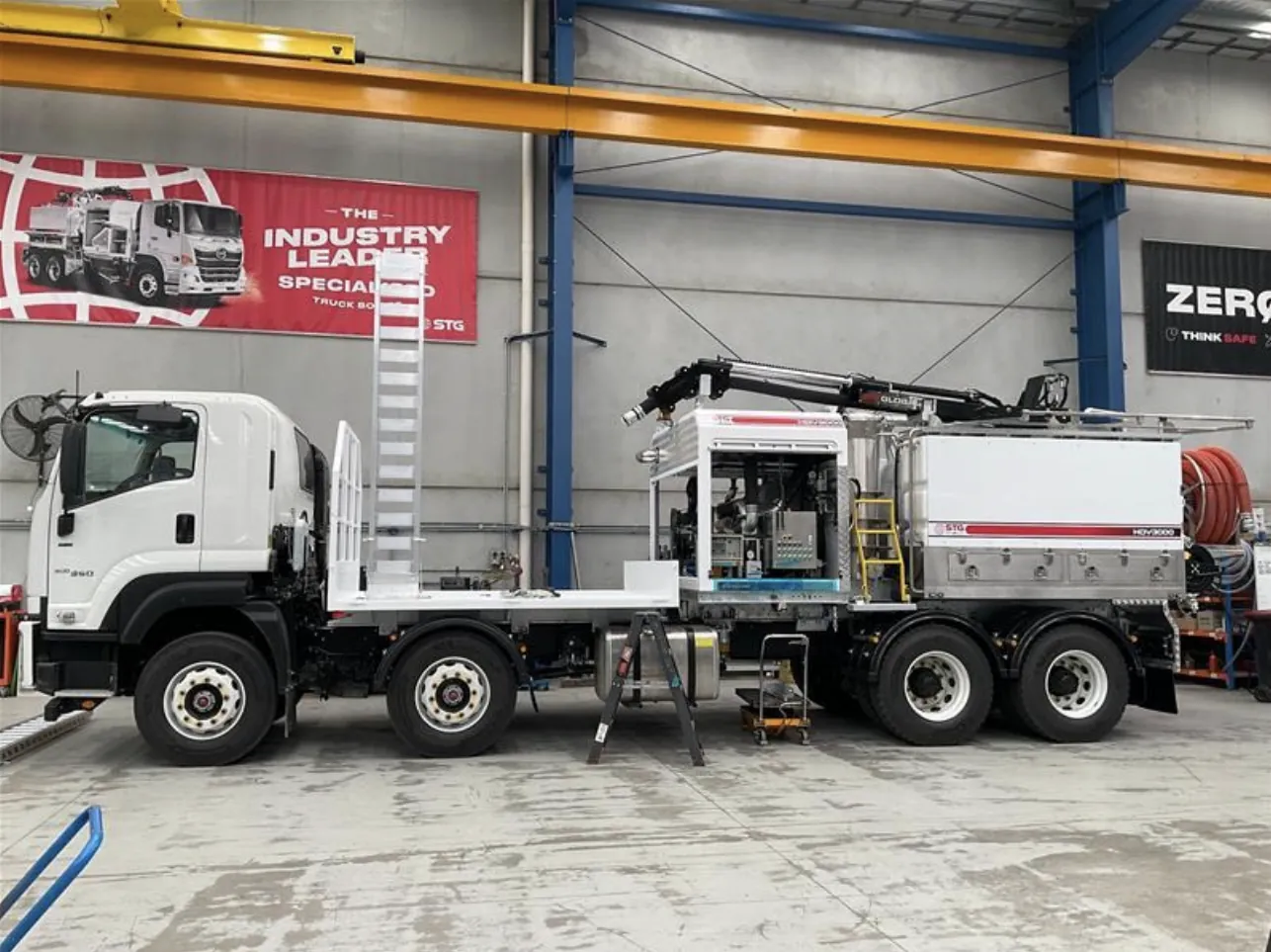 Hydro vac truck with tank and equipment fitted inside the workshop White Isuzu truck chassis with hydro vac tank, hose reel and equipment cabinet fitted, parked inside a workshop