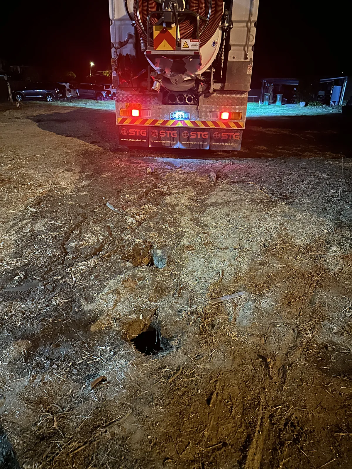 Small ground openings and marked soil in front of the illuminated rear of the truck at night