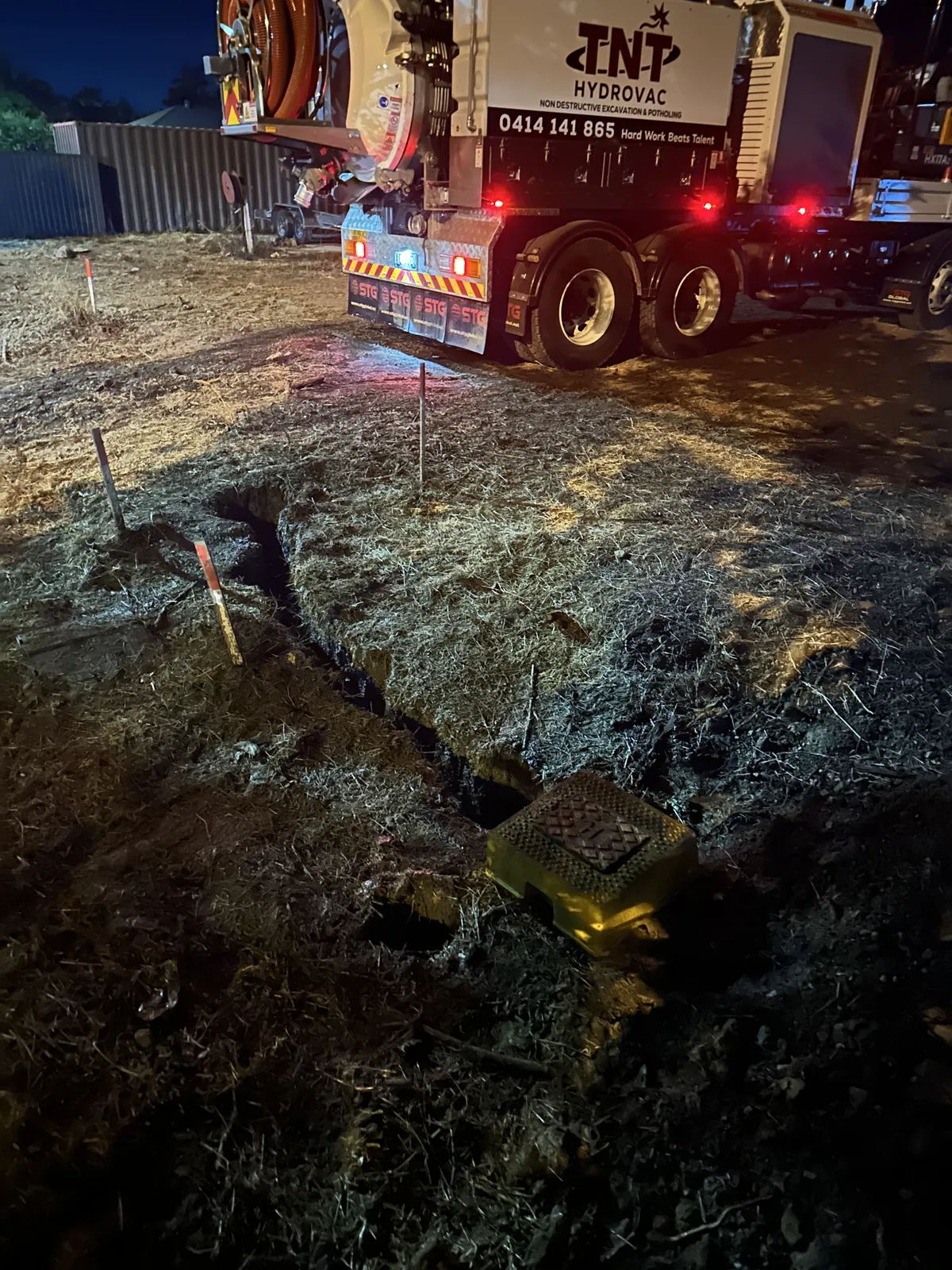 Night potholing beside the truck Lit ground openings and excavated soil beside the rear of the truck at night