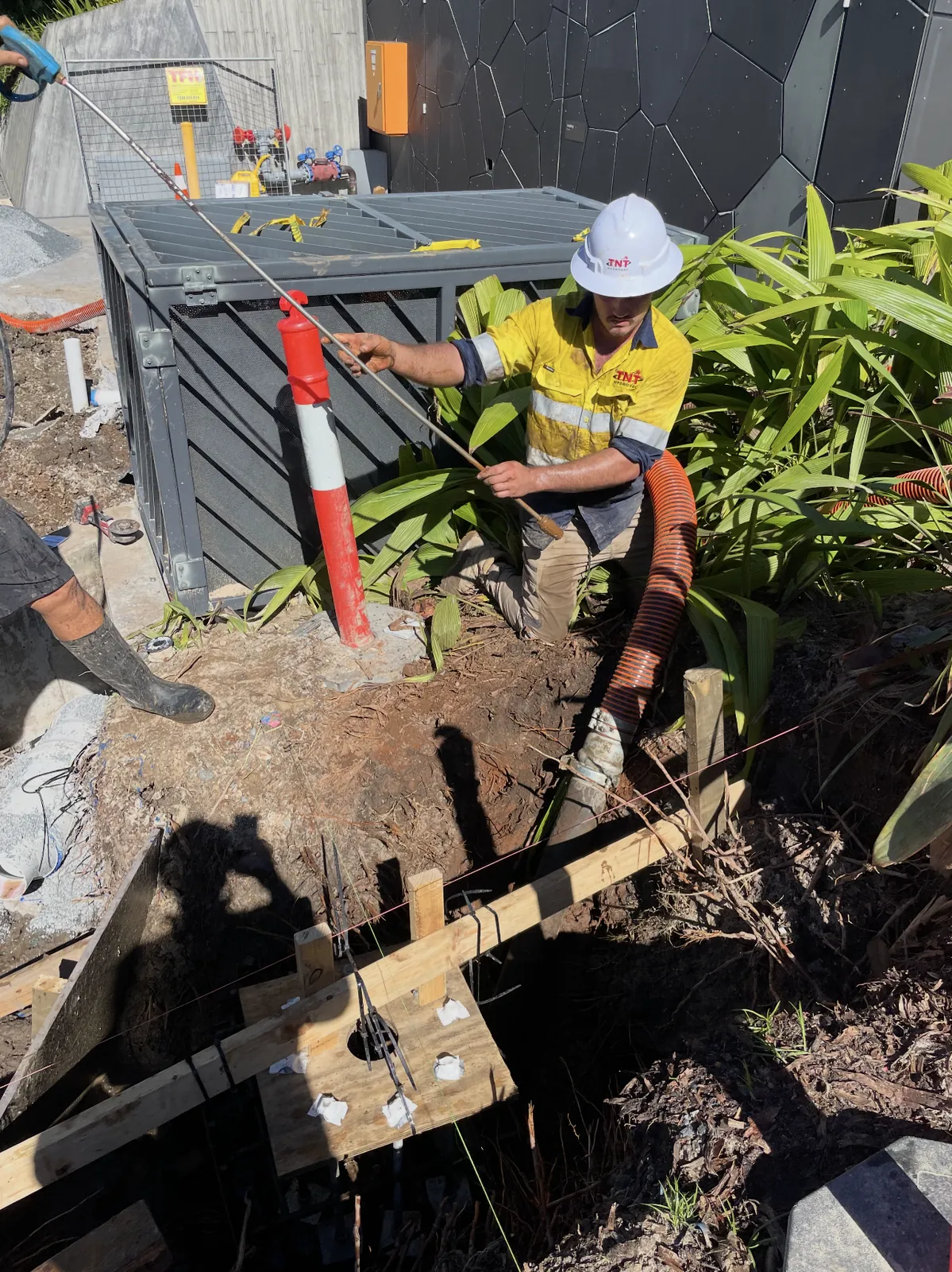 Potholing beside an electrical pillar Worker holding a water lance beside an electrical pillar with a vacuum hose and open excavation